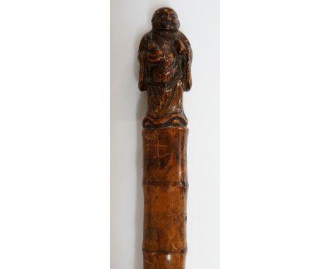 A 19th Century bamboo walking stick the terminal carved with a figure of Hotei ?, brass ferrule, 87cm long