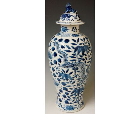 A Chinese blue and white baluster vase decorated in under glaze blue with twin dragons on a ground of chrysanthemum, bamboo a
