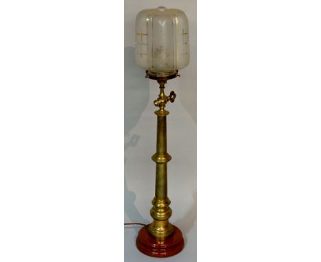 A columnar brass lamp of tapered knopped design on ceramic circular foot with a panelled and etched glass shade with gilt det