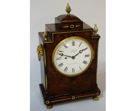 A Regency mahogany mantel clock of stepped form with three pineapple finials, ebonised and brass strung throughout the white 