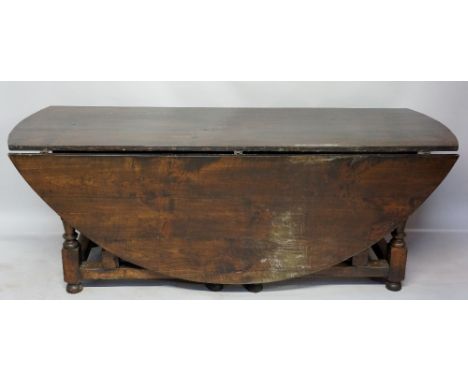 A massive reproduction fruitwood gate leg table in late 17th Century style, the oval top above bobbin and vasular turned legs