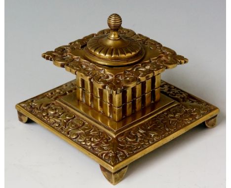 A Victorian brass inkwell the hinged domed cover with reeded ball finial borders cast leafage and masks, 10.5cm wide, 8cm hig