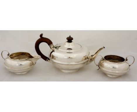 A three piece tea service of compressed globular design wtih reeded girdles, mahogany fittings, 14cm high max., by W. Neale L