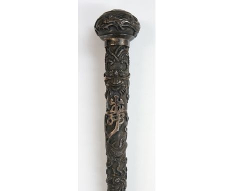 A Chinese silver walking stick handle the tapered body finely cast with bamboo, leafage, dragon and text the pommel with drag