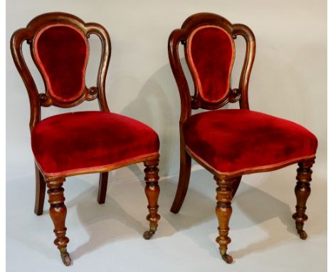 A pair of Victorian mahogany dining chairs with shaped upholstered backs and stuffed over seats on turned legs fitted brass s