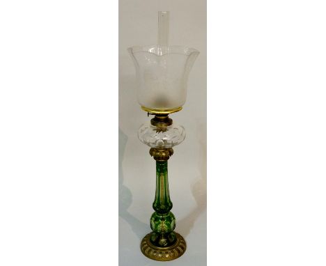 A Victorian cased green glass oil lamp the column star and panel cut with clear glass cut reservoir, acid etched shade, brass