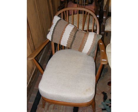 A light wood low seated retro Ercol armchair with cushioned herringbone seat and decorative cushion