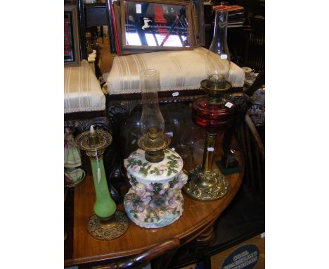 A flower and cherub sculpted Continental oil lamp together with other Victorian oil lamps 
