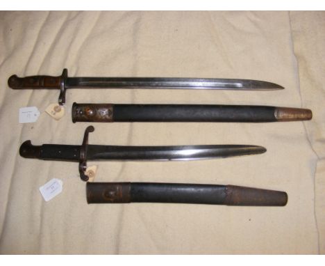 An American Remington sword bayonet in scabbard - length of bayonet 55cm, together with another bayonet in scabbard 