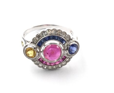 18ct white gold ring set with central cabochon ruby calibre cut rubies multi sapphires and diamonds. Approximately 1ct gems a