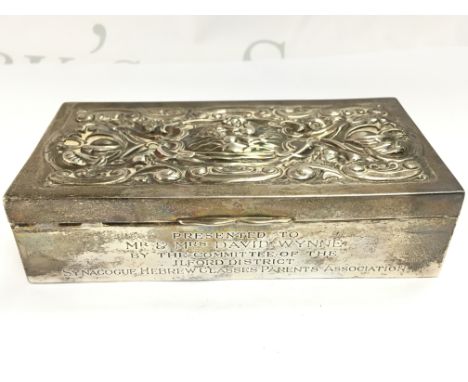 A silver cigarette box with a raised top decoration of a cherub and front side panel engraving. Dimensions 7.5x15x4cm Postage