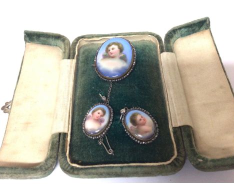 An Early 20th century enamel jewellery set decorated with cherubs and oval brooch with matching earrings. in a velvet case.