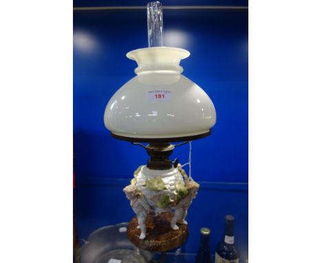 A CONTINENTAL CERAMIC OIL LAMP supported by cherubs