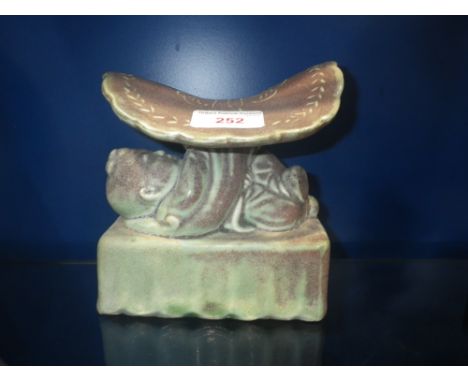 A CHINESE GLAZED CERAMIC PILLOW supported by a study of a child, 14cm wide