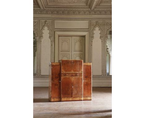 An Art Deco walnut crossbanded breakfront cocktail cabinet,  with a raised central section opening to reveal mirrored compart