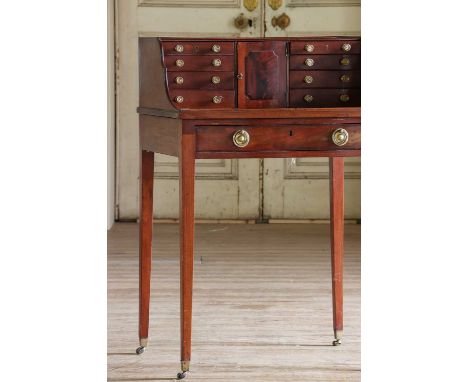 A small mahogany desk with a raised back, 19th century and later, fitted with a bank of eight small drawers and a cupboard, t