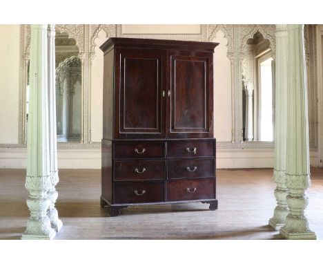 An early George III mahogany linen press,the dentil moulded cornice above a shelved upper half, enclosed by figured panel doo