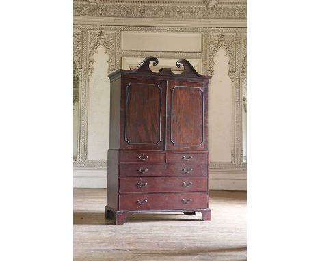 A Regency mahogany press, with a swan-neck break-arch pediment, the top half with panelled doors above drawers, on bracket fe