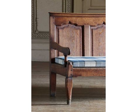 A George III oak and mahogany crossbanded settle,with an arched panel back and open arms, on cabriole legs,185cm wide66.5cm d