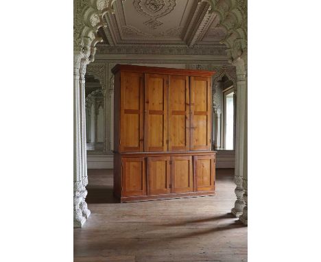 A Victorian pine estate cupboard,with pigeonholes enclosed by panel doors to the upper half and doors below, on a plinth base