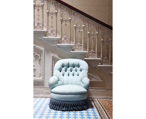 A button-upholstered spoon-back armchair,early 20th century, raised on turned mahogany legs and brass castors, upholstered in