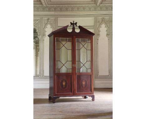 A mahogany hanging cupboard,19th century, the break arch pediment having an eagle finial, over astragal glazed and inlaid doo