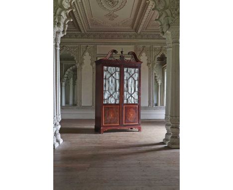 An Edwardian mahogany hanging cupboard,with astragal glazed and inlaid panel doors, a swan-neck fret-carved pediment, on brac