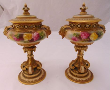 A pair of Royal Worcester pot pourri holders of compressed cylindrical form decorated with flowers, leaves and mask side hand