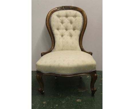 A Victorian nursing chair, carved hoop back upholstered in cream on ceramic casters