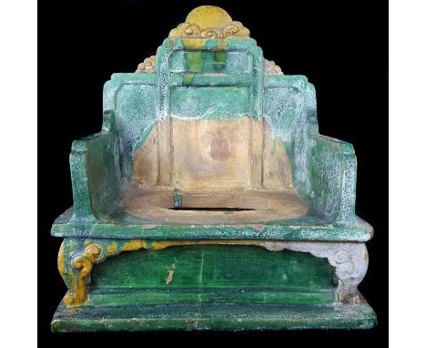 A Chinese Ming dynasty pottery Emperors throne chair, Sancai glazed in green and yellow, the stepped back surmounted with a c