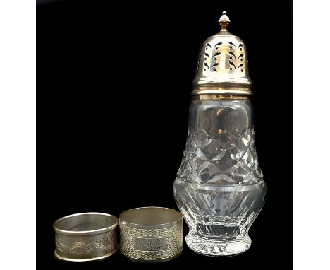 A silver topped cut glass sugar caster, of vase form, Birmingham 1963; and two silver napkin rings (3)