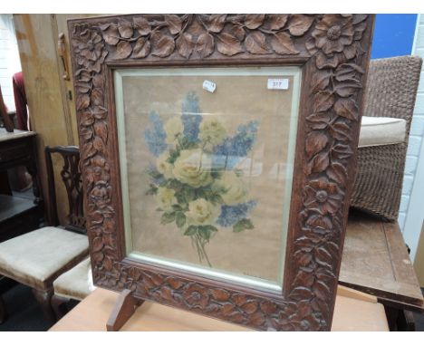 An early 20th century oak frame firescreen having foliate carved decoration and watercolour inset