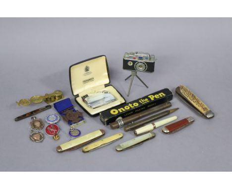 Two silver sporting medals; a brass sovereign scale; two cigarette lighters; three various pens; &amp; six pocketknives. 