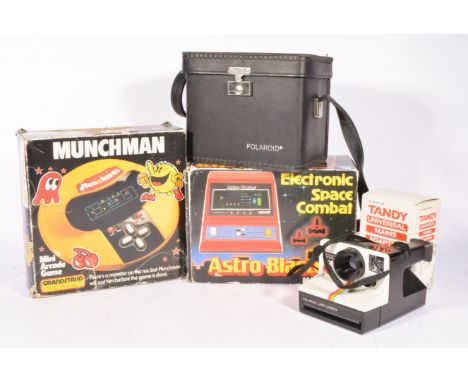 Mates Astro Blaster electronic game, Tomy Munchman game and a Polaroid camera, all boxed.