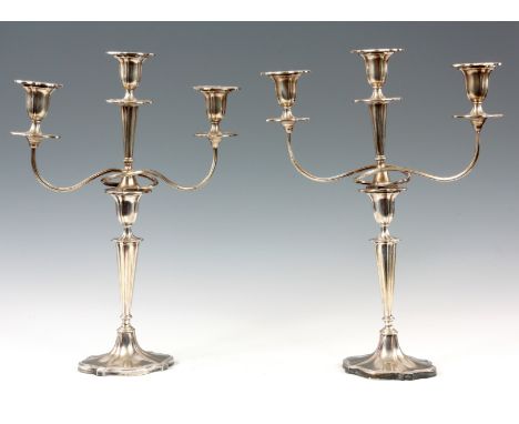 A PAIR OF WALKER AND HALL SHEFFIELD THREE BRANCH SILVER PLATED CANDELABRA with scalloped oval candlestick bases 41.5cm high.