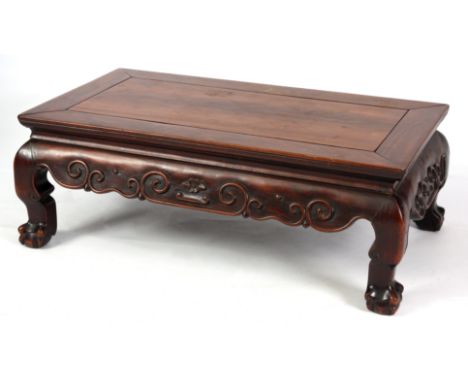 A 19TH CENTURY CHINESE HARDWOOD LOW OCCASIONAL TABLE with panelled top and shaped scroll carved base on short legs with claw 