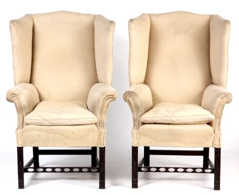 A PAIR OF 19TH CENTURY WINGBACK MAHOGANY UPHOLSTERED ARMCHAIRS with Chinese Chippendale style blind fret legs joined by pierc