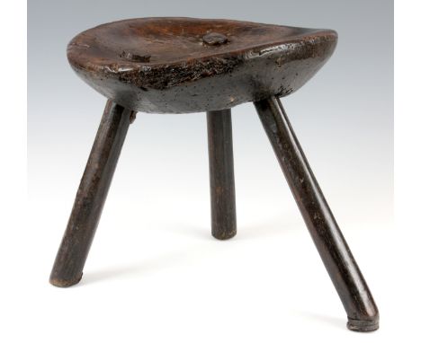 AN 18th CENTURY PRIMITIVE OAK THREE-LEGGED STOOL with dished seat and stick legs 32cm diameter 32cm high.