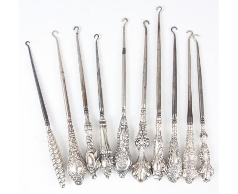 A COLLECTION OF TEN LARGE EDWARDIAN STERLING SILVER HANDLED BUTTON HOOKS with embossed&nbsp;tops - hallmarked 20cm and smalle