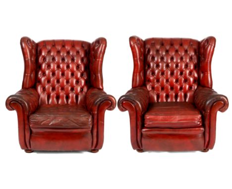 A PAIR OF RED LEATHER BUTTON BACKED WING BACKED ARMCHAIRS with shaped backs and loose cushion seats.&nbsp;