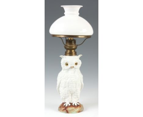 A LATE 19TH CENTURY PORCELAIN OIL LAMP MODELLED AS AN OWL with brass burner and white glass shade, the owl having glass eyes.