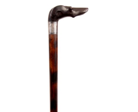 AN EARLY 20th CENTURY CARVED DOG&rsquo;S HEAD EBONY HANDLED WALKING CANE mounted on walnut stick having glass eyes and silver