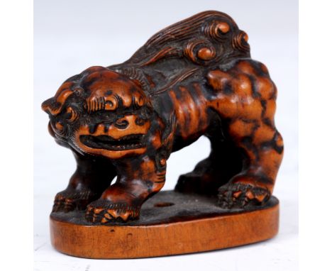 A JAPANESE BOXWOOD NETSUKE of a Foo Dog stood on plinth base, signed to underside.