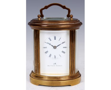 MATHEW NORMAN A SWISS MADE BRASS OVAL SHAPED CARRIAGE CLOCK the enamel dial with Roman numerals fronting a jewelled eight-day