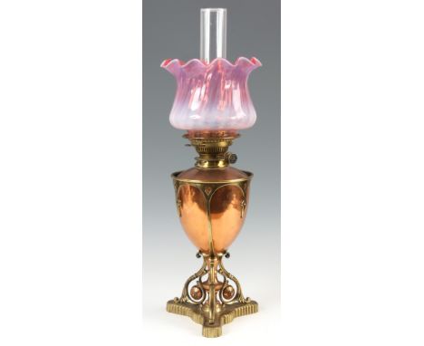 A LATE VICTORIAN GOTHIC STYLE COPPER AND BRASS OIL LAMP with stylised base and pink vaseline shaped shade 50cm high.