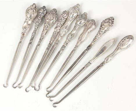 A COLLECTION OF TEN EDWARDIAN STERLING SILVER HANDLED BUTTON HOOKS with embossed&nbsp;tops - hallmarked 20cm and smaller.&nbs