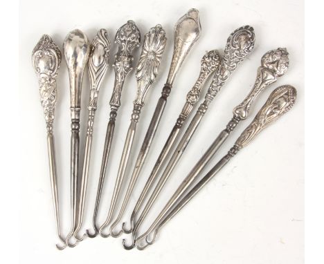 A COLLECTION OF TEN EDWARDIAN STERLING SILVER HANDLED BUTTON HOOKS with embossed&nbsp;tops - hallmarked 20cm and smaller.&nbs