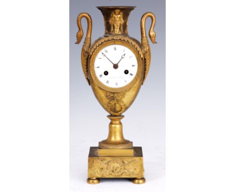 A FRENCH EMPIRE ORMOLU URN-SHAPED MANTEL CLOCK surmounted by two swan heads, the case with acanthus leaf and dragonfly decora