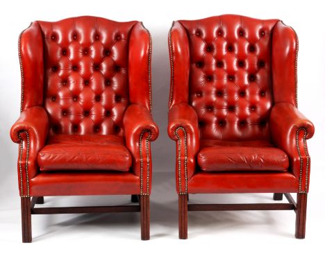 A PAIR OF 19TH CENTURY STYLE RED LEATHER BUTTON BACKED WINGED ARMCHAIRS with deep buttoned backs, swept shaped sides and loos