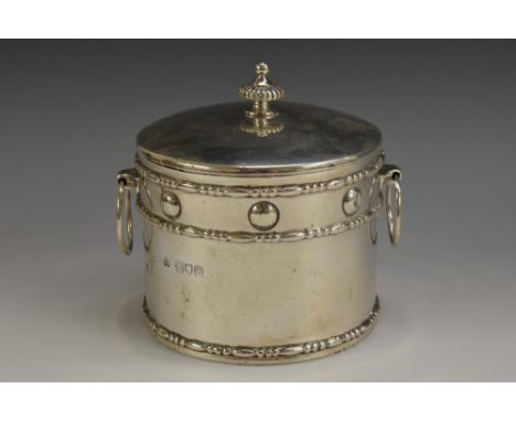 An Edwardian silver circular tea caddy, push-fitting cover with fluted knop finial, ring handles, the side embossed in the Ar